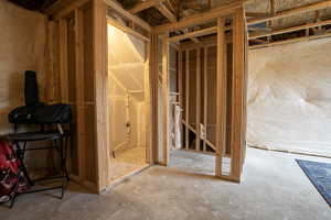 Unfinished basement space featuring visible wood framing, concrete flooring, and exposed ceiling joists