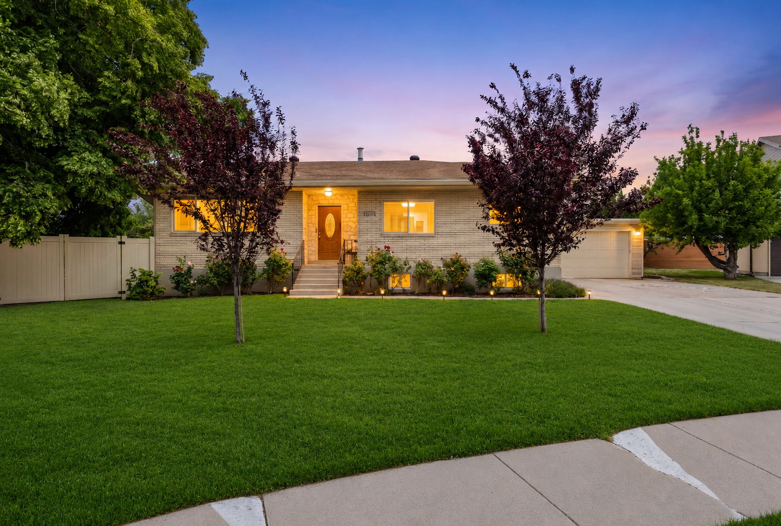 Brick facade residence featuring a front lawn with two ornamental trees
