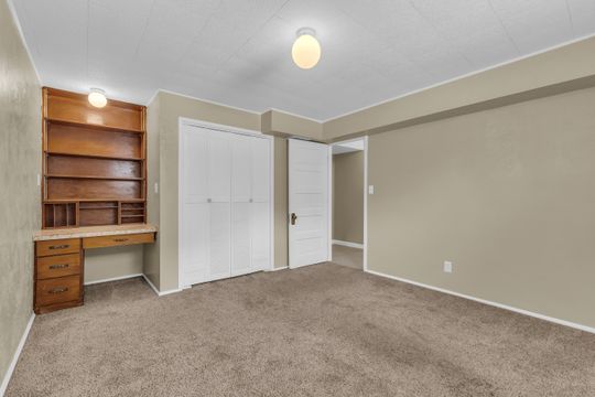 Spacious room featuring neutral carpeting, a built-in wood-finish desk with hutch, and two ceiling-mounted globe light fixtures