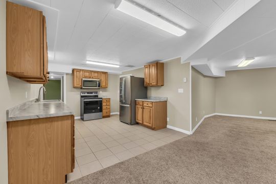 Kitchenette featuring wood cabinetry, stainless steel appliances, and a tile floor