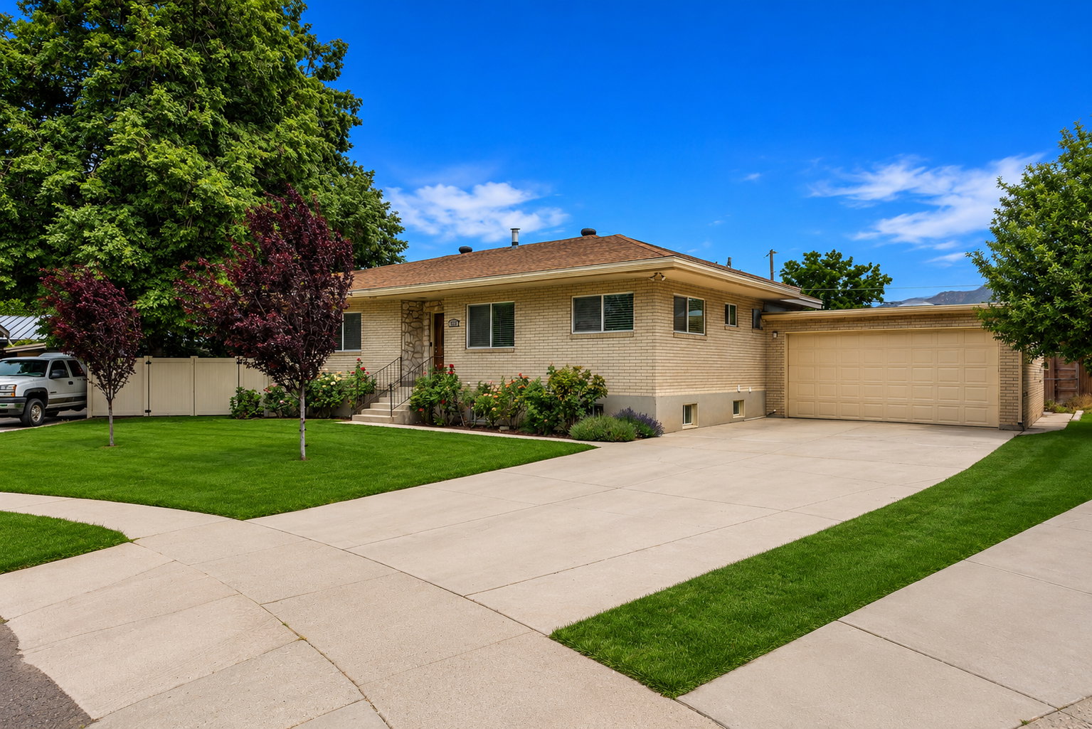 Light brick exterior with a tan roof, featuring a concrete driveway and an attached garage
