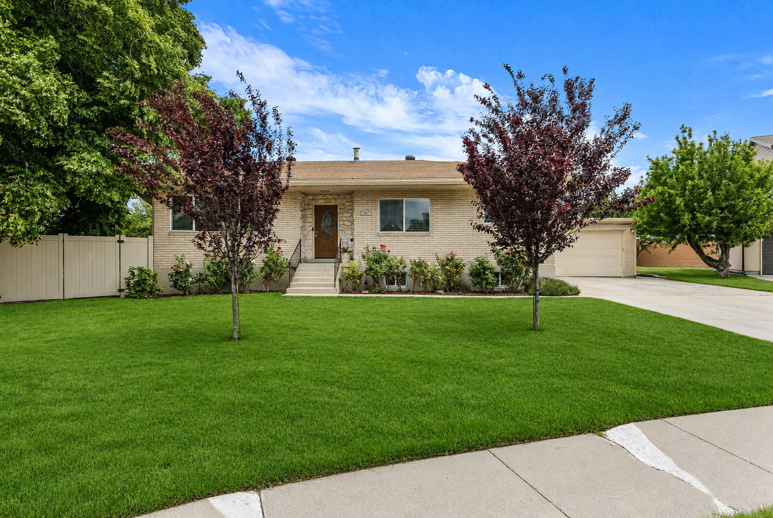 Ranch-style residence featuring a brick facade, mature landscaping, and a well-maintained lawn