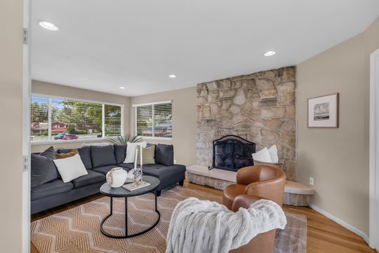 Living area featuring a stone accent wall with a fireplace, recessed lighting, and wood-finish flooring