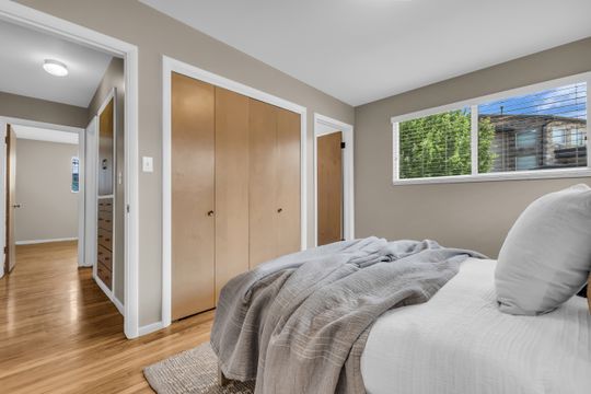 Bedroom featuring wood-finish flooring, a window with blinds, and built-in closet storage