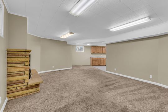 Spacious interior featuring a stacked stone fireplace, plush carpeting, warm neutral wall tones, and recessed lighting