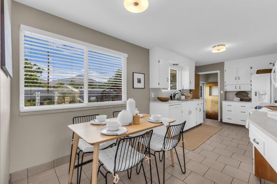Bright kitchen with tile flooring, white cabinetry, a sink with window, and recessed lighting