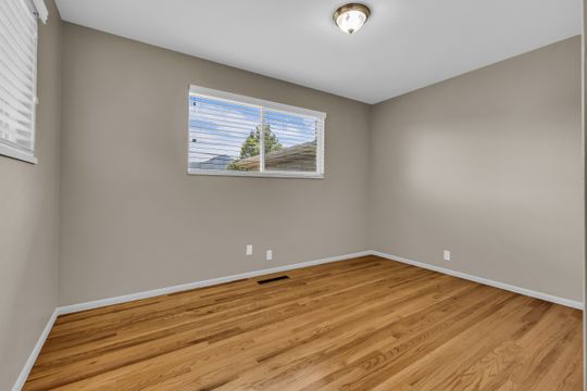 Room featuring hardwood flooring, neutral wall paint, and a window with horizontal blinds