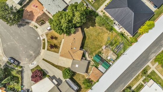Aerial property overview featuring a cul-de-sac location, paved driveway, mature trees, and an expansive rear yard