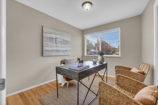 Room featuring natural wood-finish flooring, a single window with blinds, light-toned wall paint, and a flush-mount ceiling light fixture