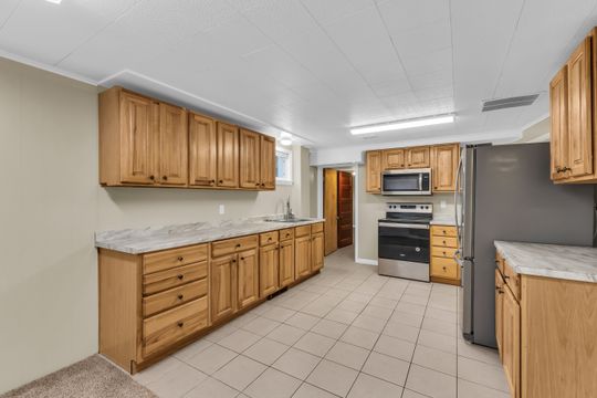Kitchen featuring wood cabinetry, light-toned countertops, and tile flooring