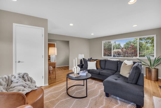Spacious living area featuring wood-finish flooring, recessed lighting, and a large window with blinds