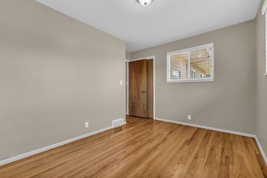Room featuring wood-finish flooring, neutral wall paint, and white trim