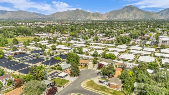 Expansive aerial perspective showcasing a residential community with mature trees and mountain scenery