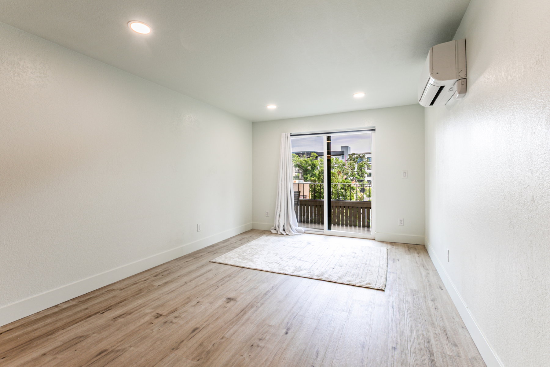 Spacious room featuring wood-finish flooring, recessed lighting, and a ductless mini-split system