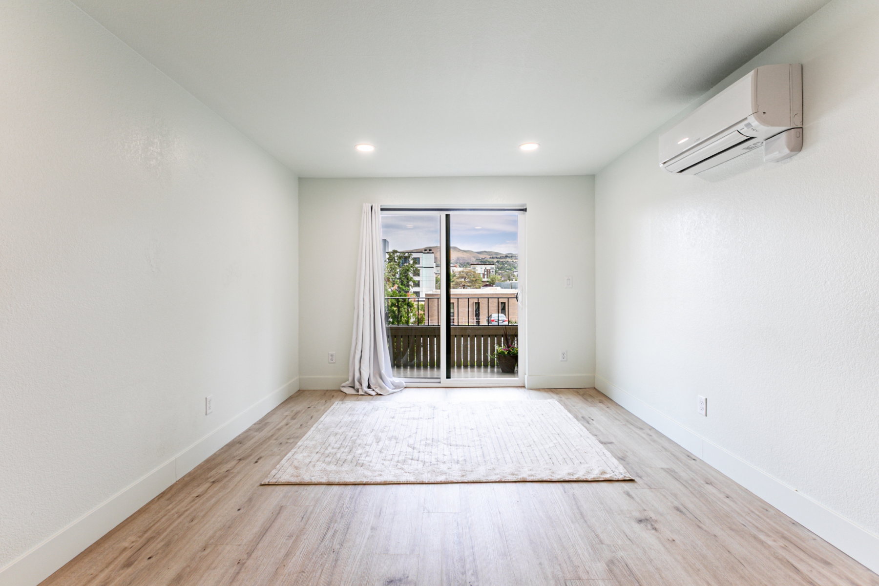 Light-filled room featuring wood-finish flooring, recessed lighting, and a sliding glass door opening to an outdoor deck