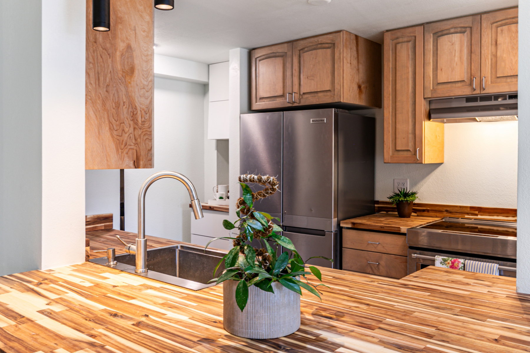 Kitchen featuring wood-finish countertops, a stainless steel double basin sink with a gooseneck faucet, and recessed lighting