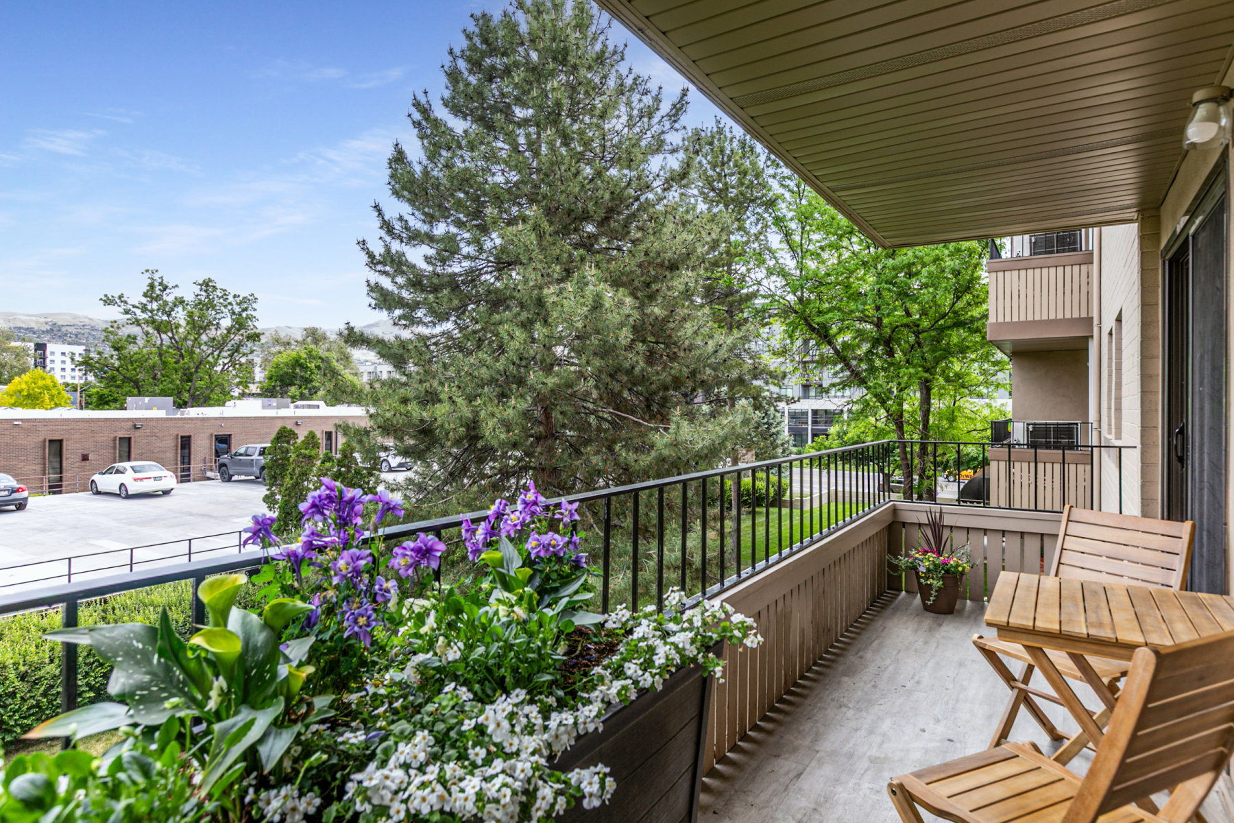 Private balcony featuring an overhead soffit, black metal railing, and wood-finish paneling
