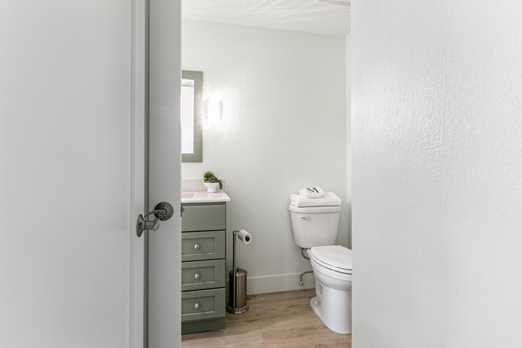 Bathroom with a sage green vanity featuring three drawers and a white countertop