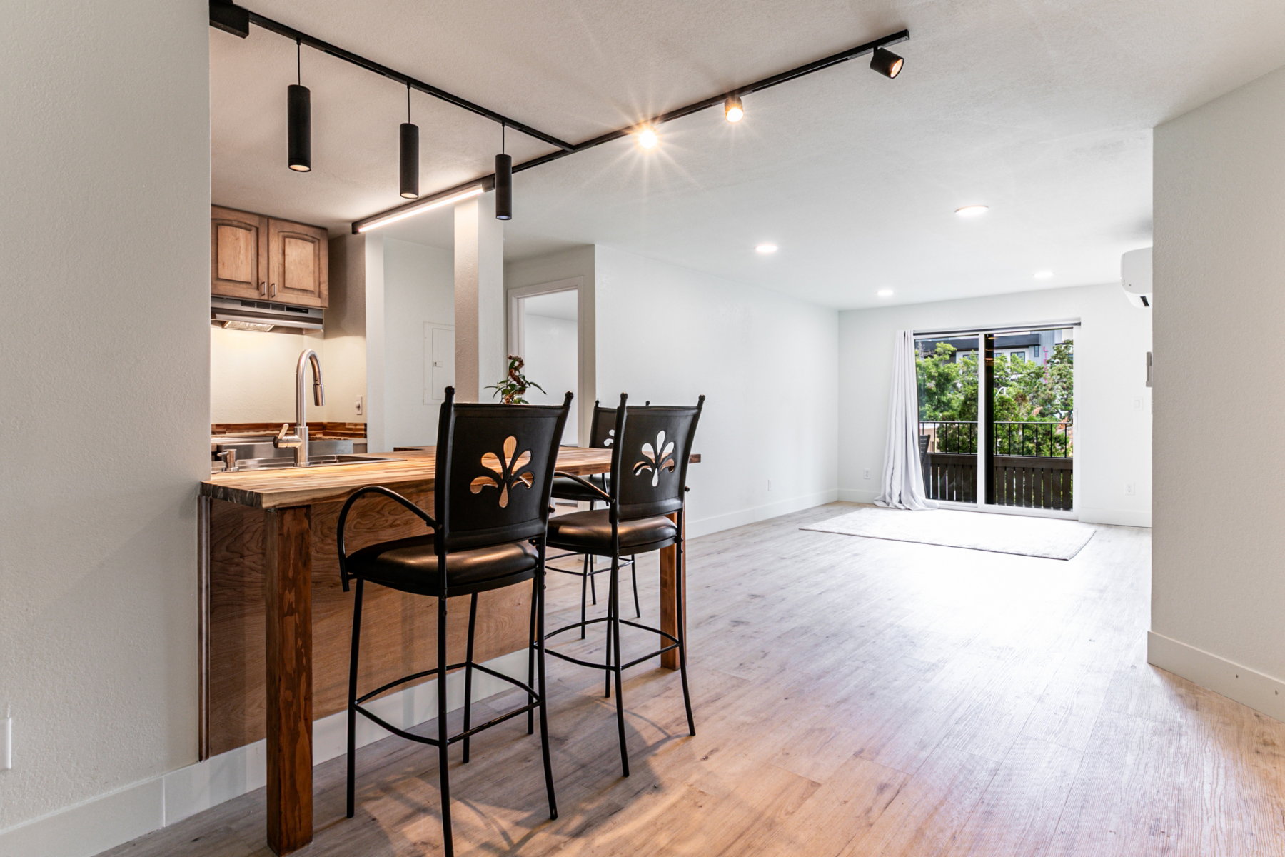 Open-concept living area featuring light wood-finish flooring and a kitchen pass-through with a natural wood countertop