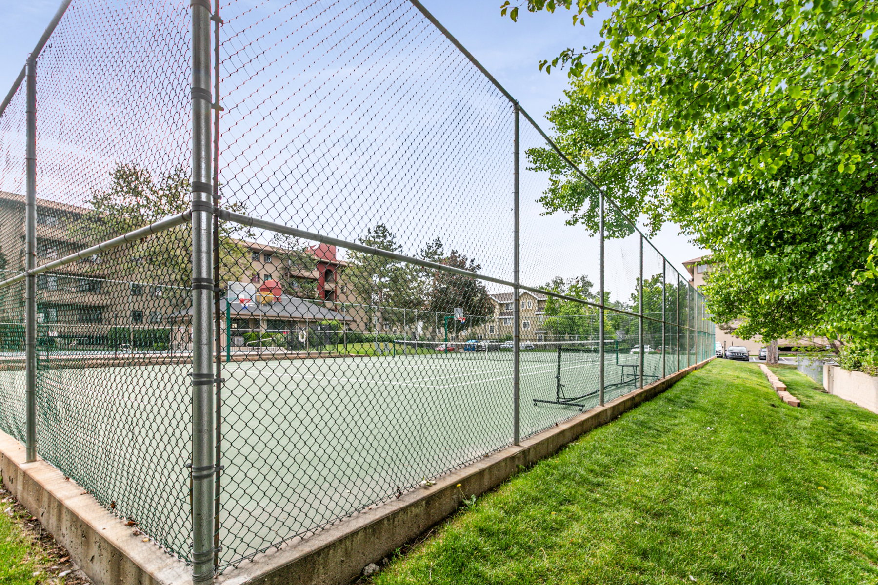 Outdoor tennis court featuring a perimeter fence and concrete base