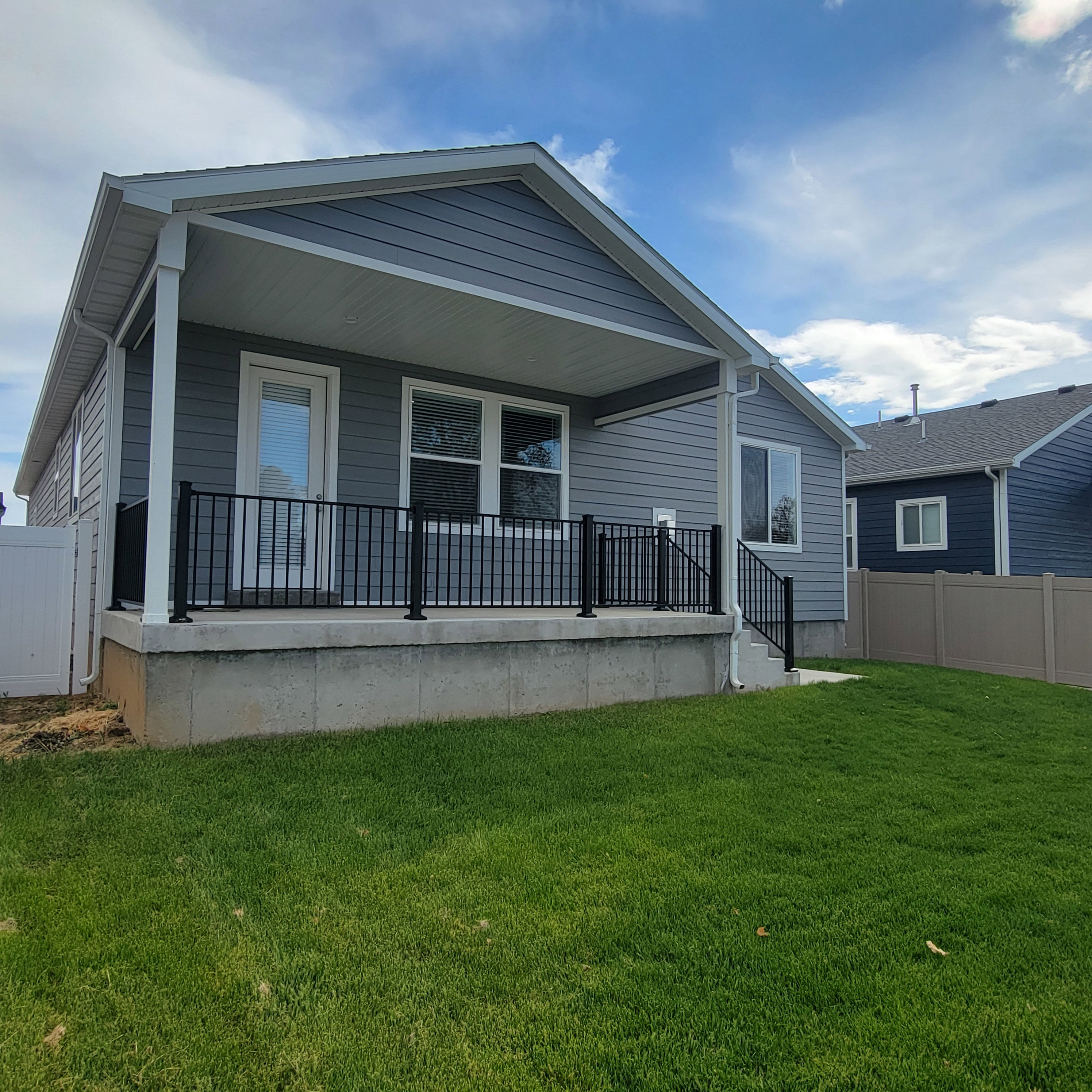 Covered concrete patio with black metal railings
