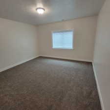 Spacious room featuring textured carpeting, white baseboards, and neutral wall paint