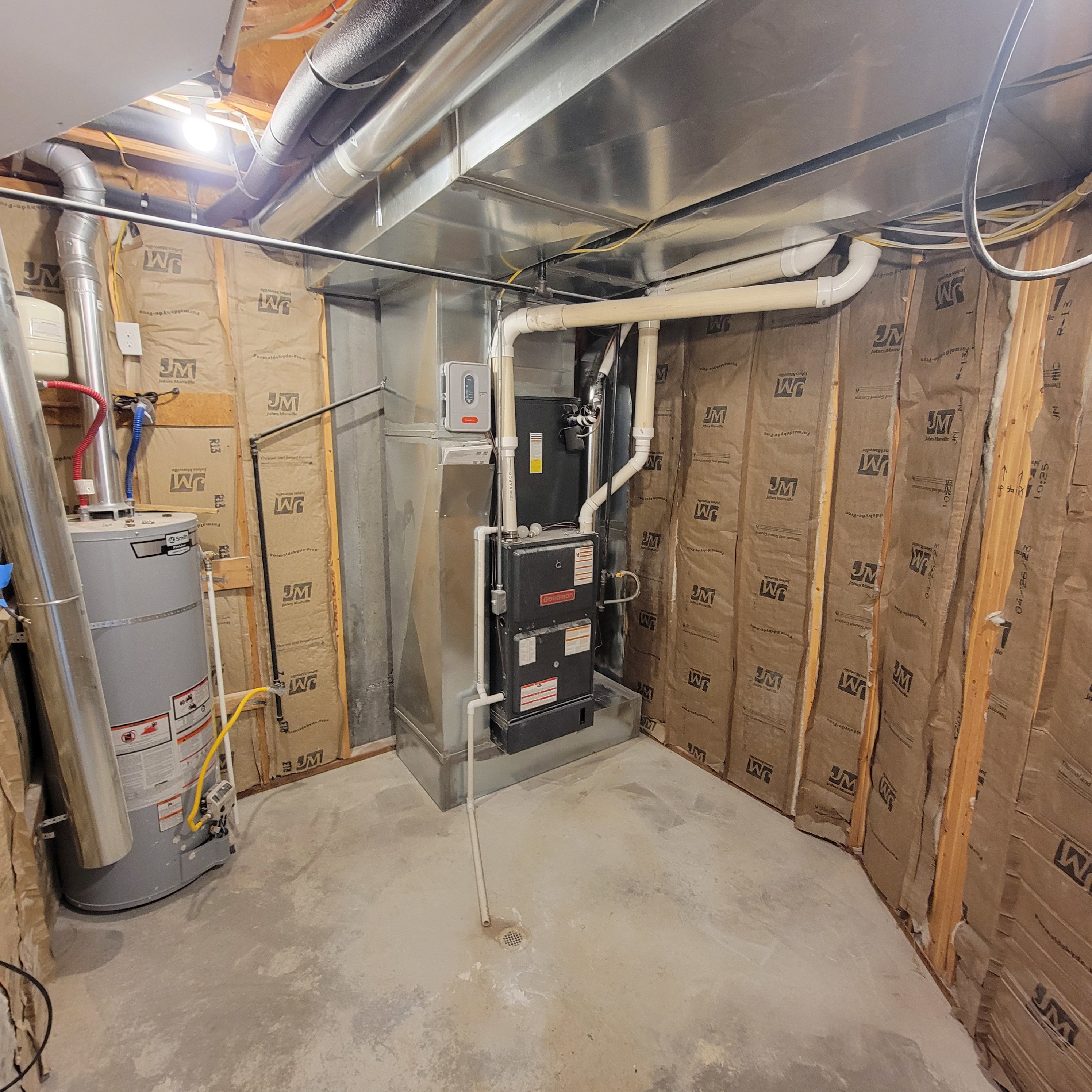 Utility area featuring a water heater, furnace, insulated walls, exposed ductwork, and concrete flooring