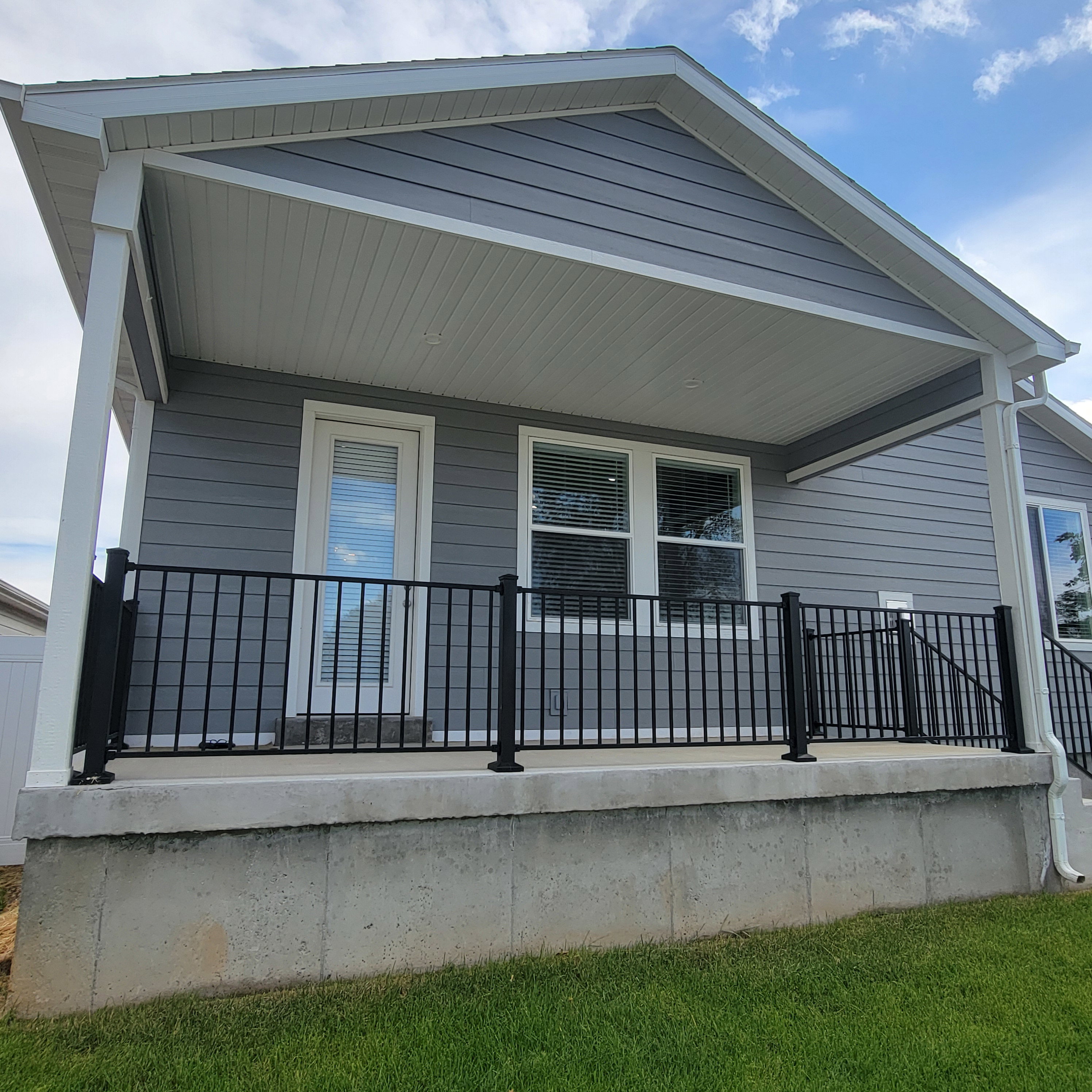 Covered patio featuring gray siding, white trim, and black metal railings