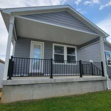 Covered patio featuring gray siding, white trim, and black metal railings