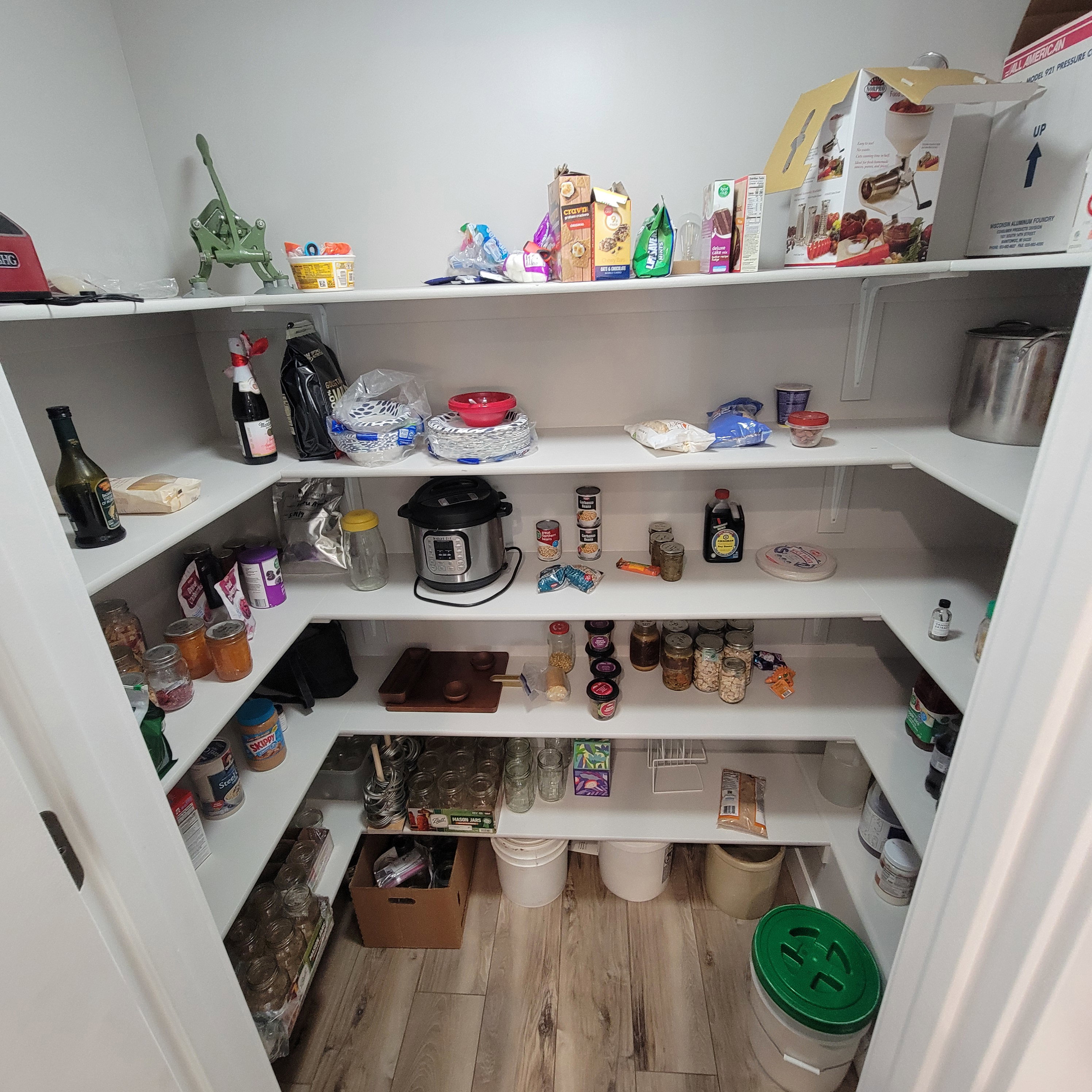 Walk-in pantry featuring extensive U-shaped shelving, light wood-finish flooring, and white walls