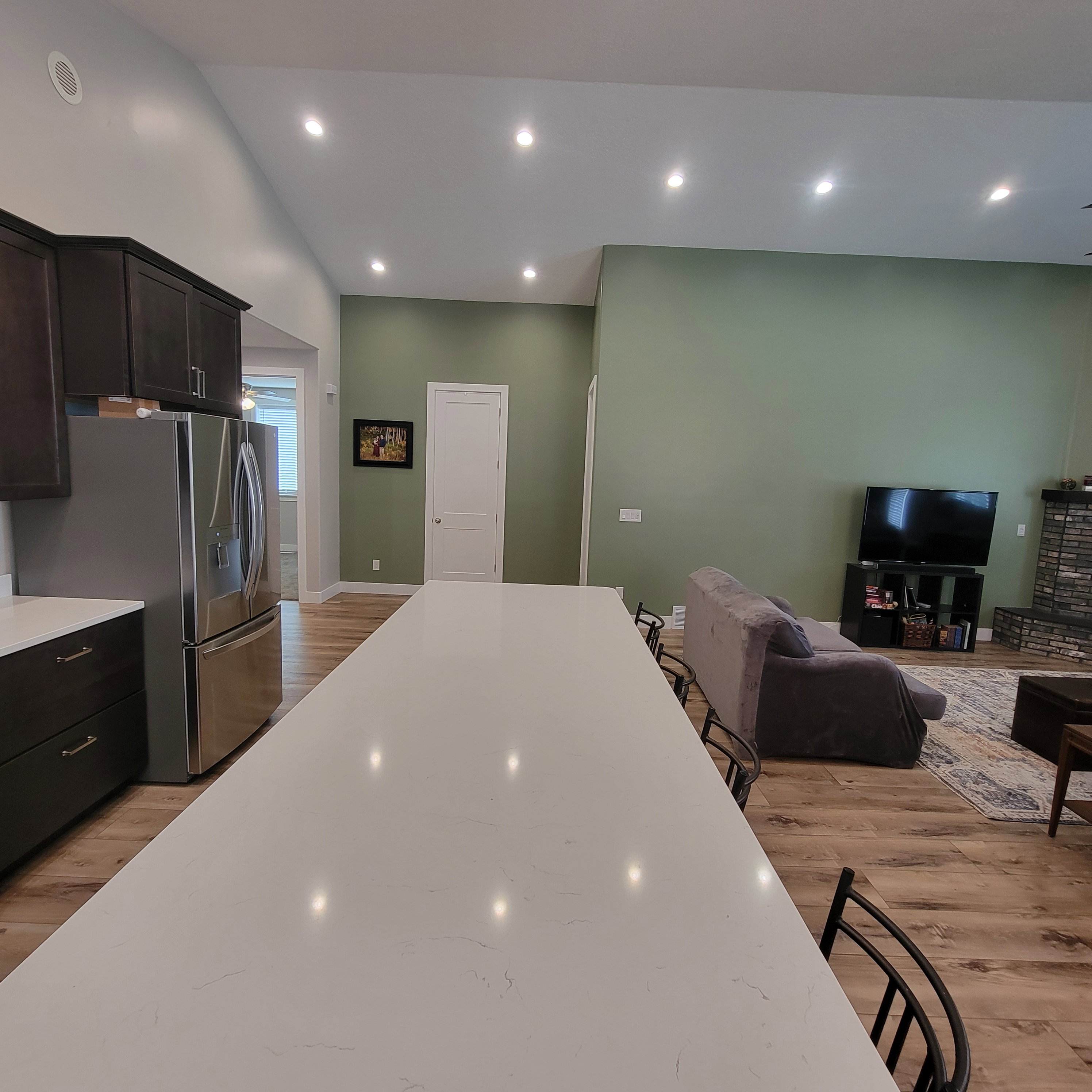 Expansive kitchen island with a light-toned countertop, dark cabinetry, and integrated stainless steel refrigerator