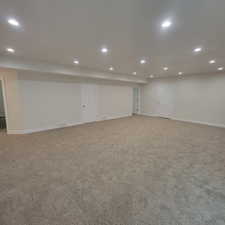 Spacious room featuring neutral carpeting, white walls, recessed ceiling lighting, and multiple interior doors