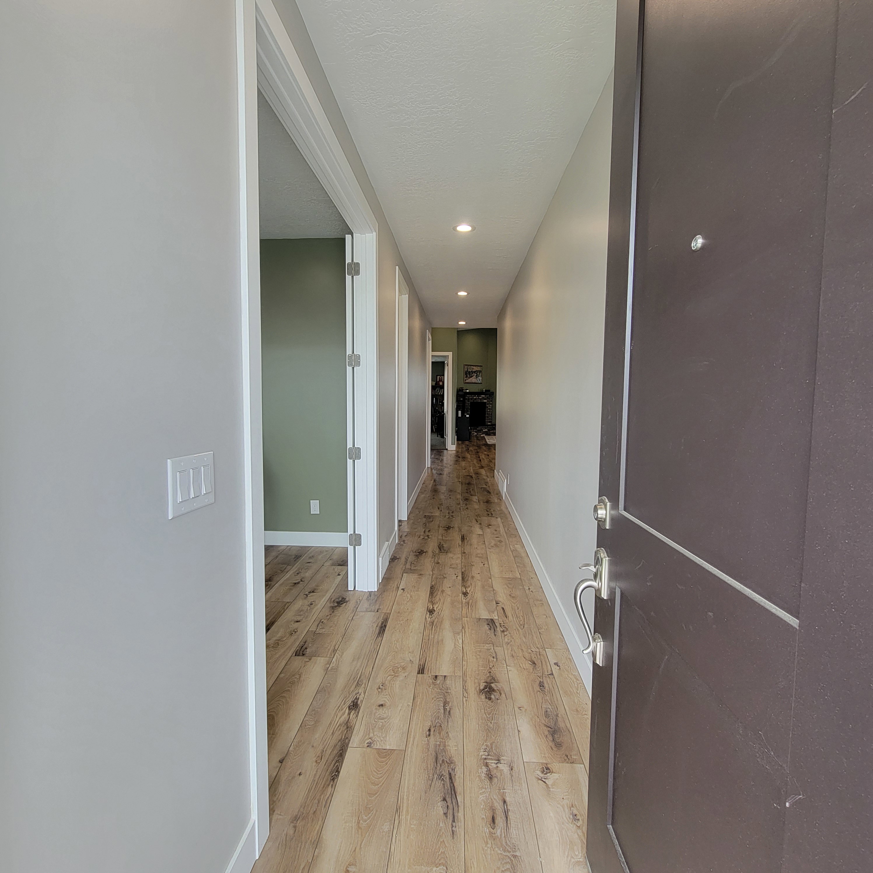 Entryway featuring a solid panel door with brushed nickel hardware, wood-finish flooring, recessed lighting, and light gray walls
