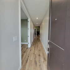 Entryway featuring a solid panel door with brushed nickel hardware, wood-finish flooring, recessed lighting, and light gray walls