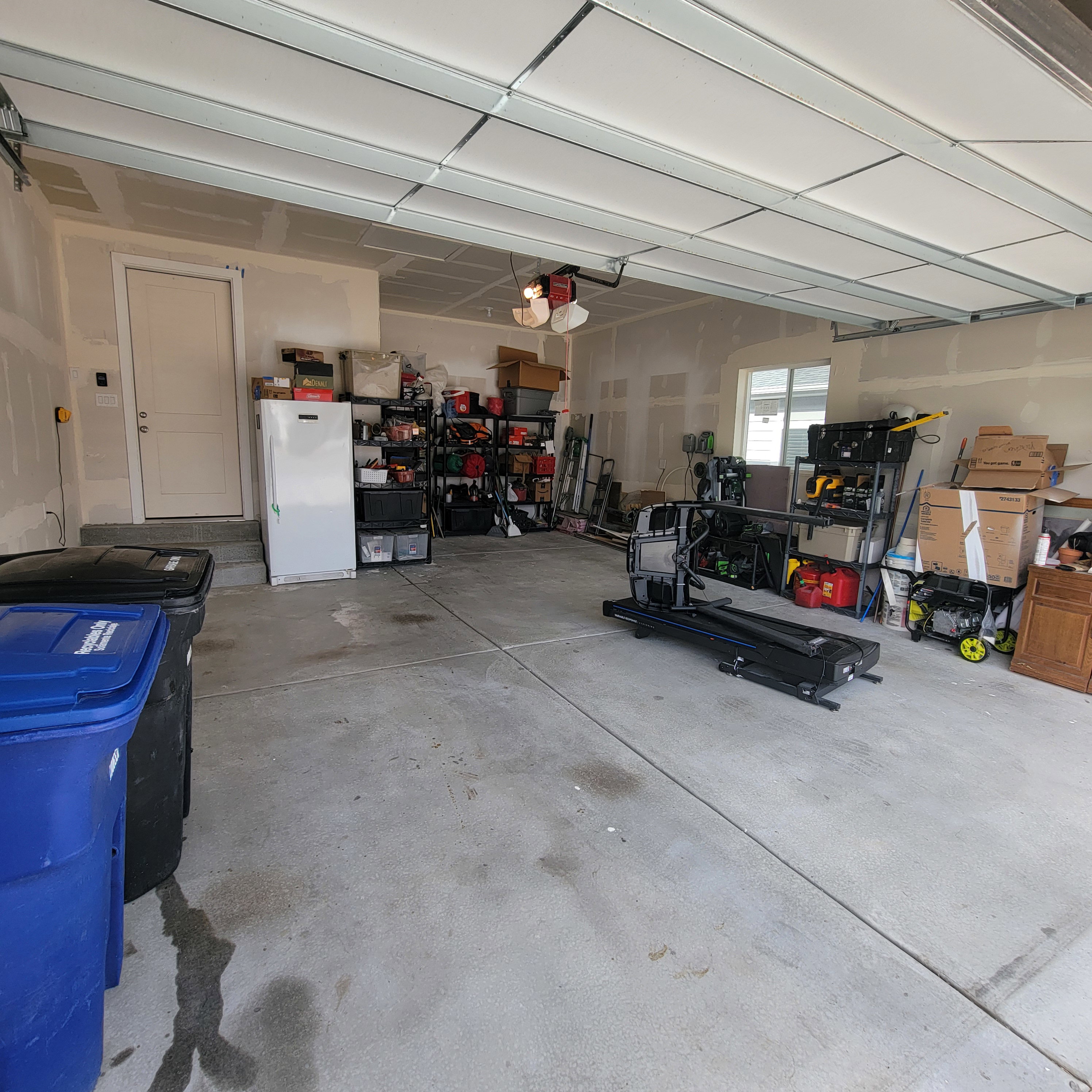 Spacious garage with exposed framing and a light-colored entry door