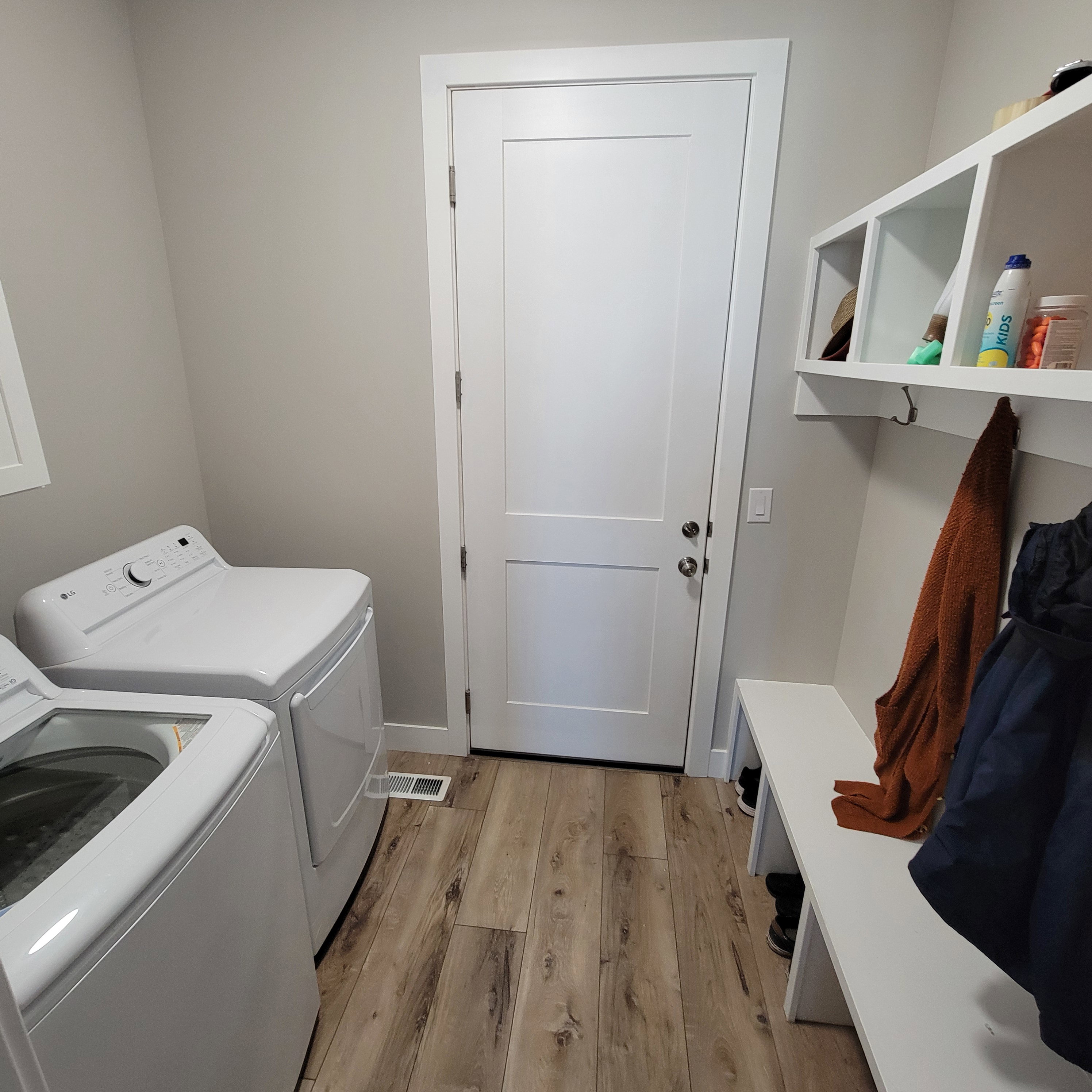 Laundry area featuring wood-finish flooring, light gray walls, and white trim