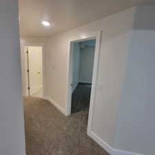 Carpeted hallway featuring bright white walls, recessed ceiling lighting, and two doorways with white trim