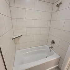 Bathtub with white subway tile surround, corner shelf, and brushed nickel fixtures