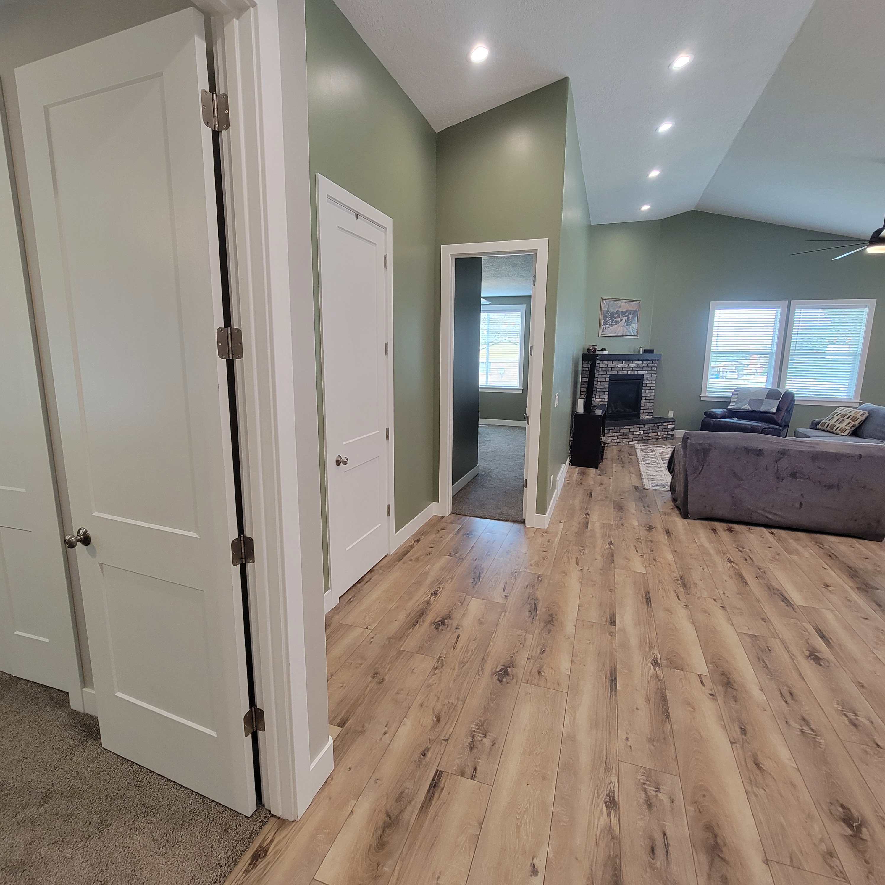 Spacious living area featuring wood-finish flooring, vaulted ceilings, and recessed lighting