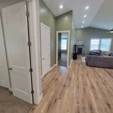 Spacious living area featuring wood-finish flooring, vaulted ceilings, and recessed lighting