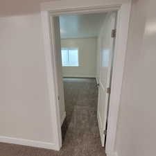 Carpeted room with a white door and trim, featuring a window with horizontal blinds