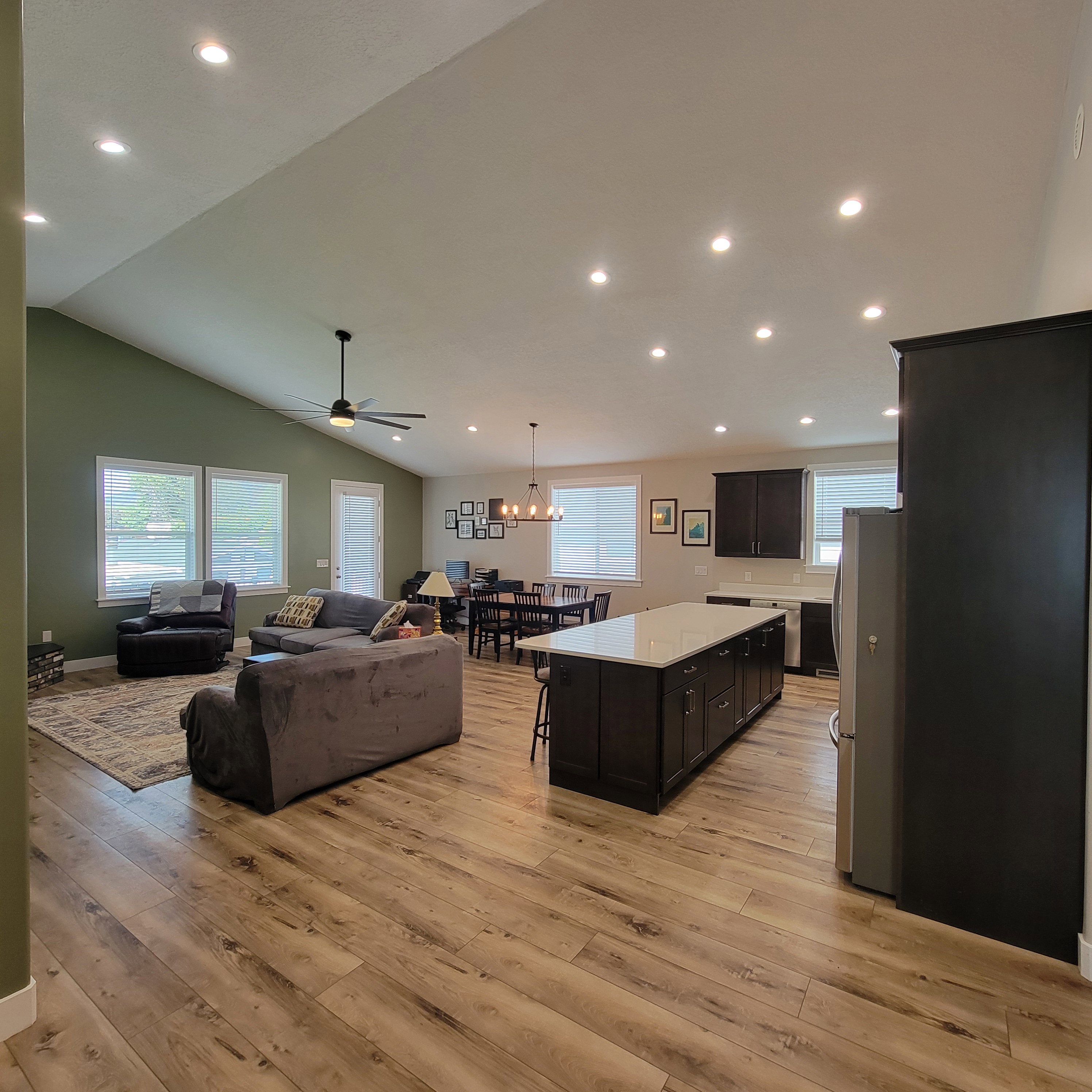 Open-concept living space featuring wood-finish flooring, recessed lighting, and a vaulted ceiling