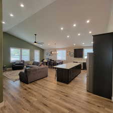 Open-concept living space featuring wood-finish flooring, recessed lighting, and a vaulted ceiling
