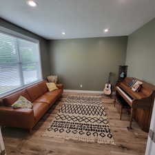 Spacious room featuring wood-finish flooring, recessed lighting, a large window with blinds, and painted walls