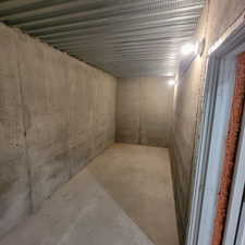 Concrete-walled room featuring a finished concrete floor, exposed metal ceiling, and wall-mounted lighting fixtures