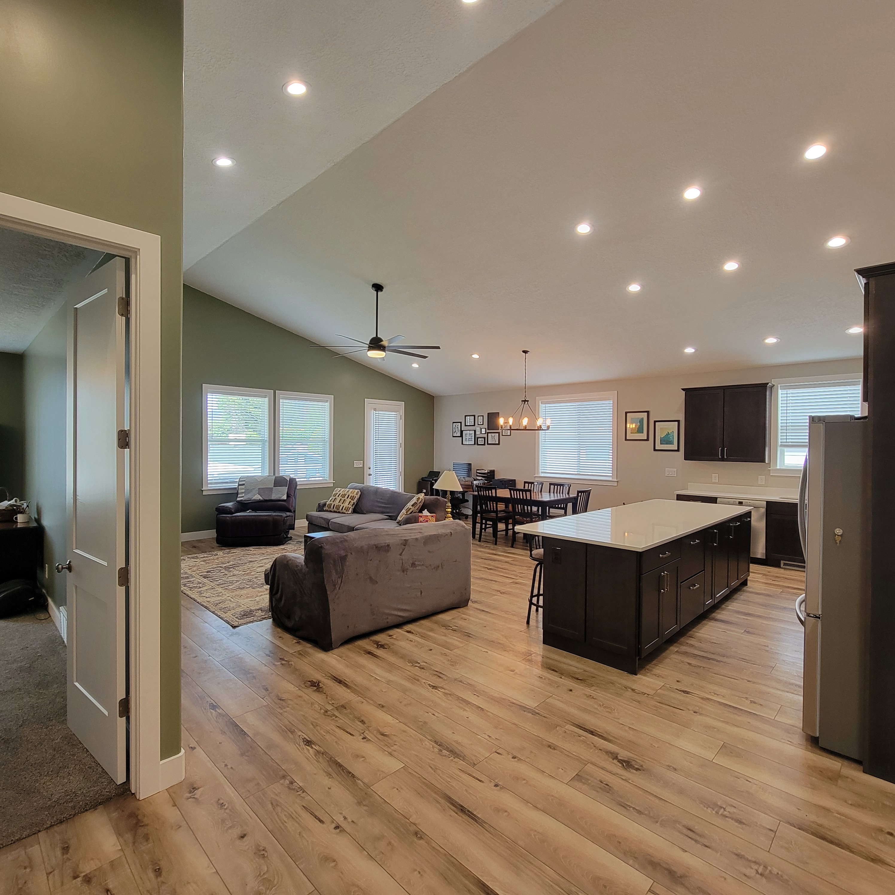 Open-concept living space featuring wood-finish flooring, recessed lighting, and a vaulted ceiling