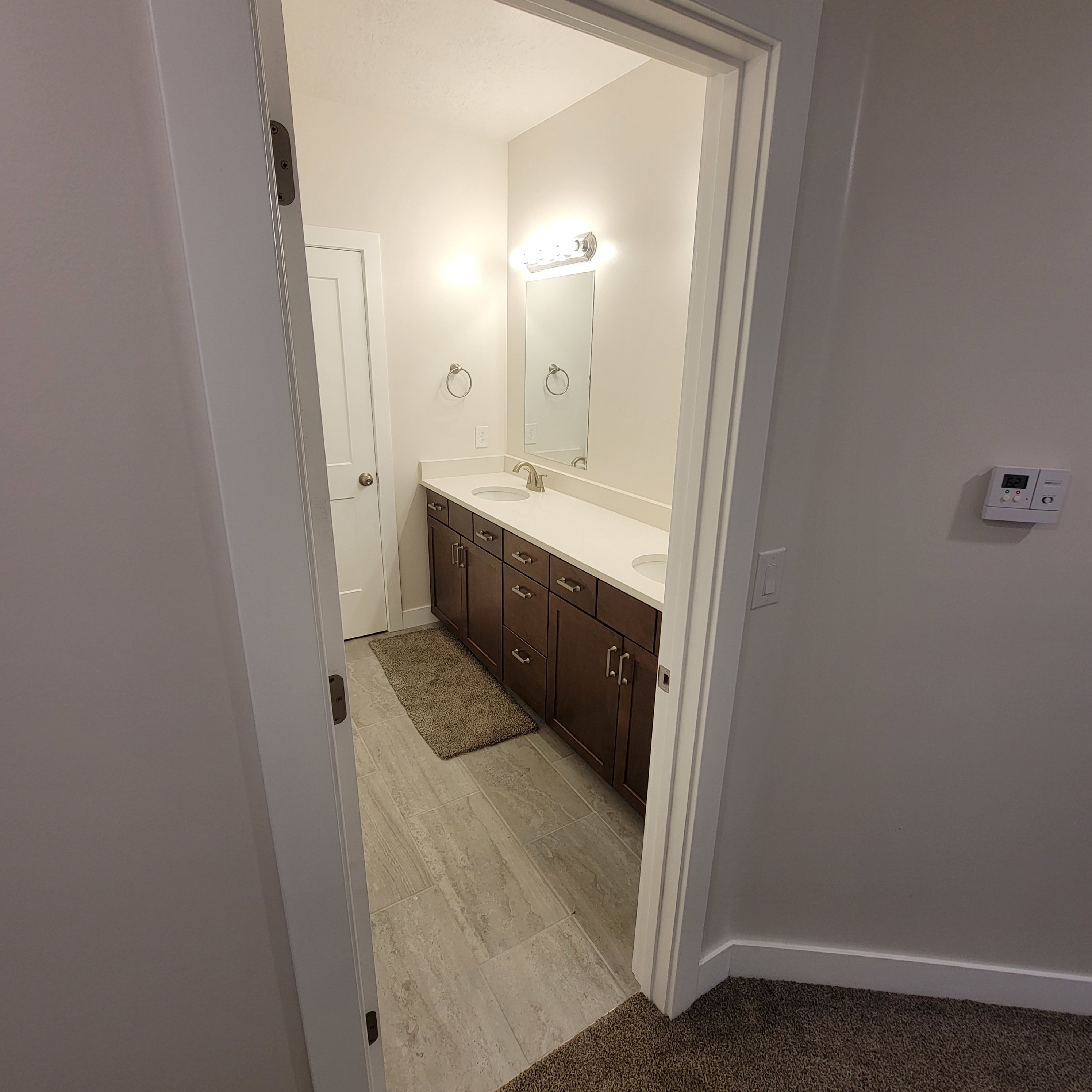 Bathroom featuring a dual vanity with dark wood cabinetry and white countertops