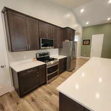 Contemporary kitchen featuring dark wood cabinetry, stainless steel appliances, and white countertops