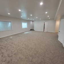 Spacious room featuring new carpeting, recessed lighting, white trim, and multiple windows with blinds