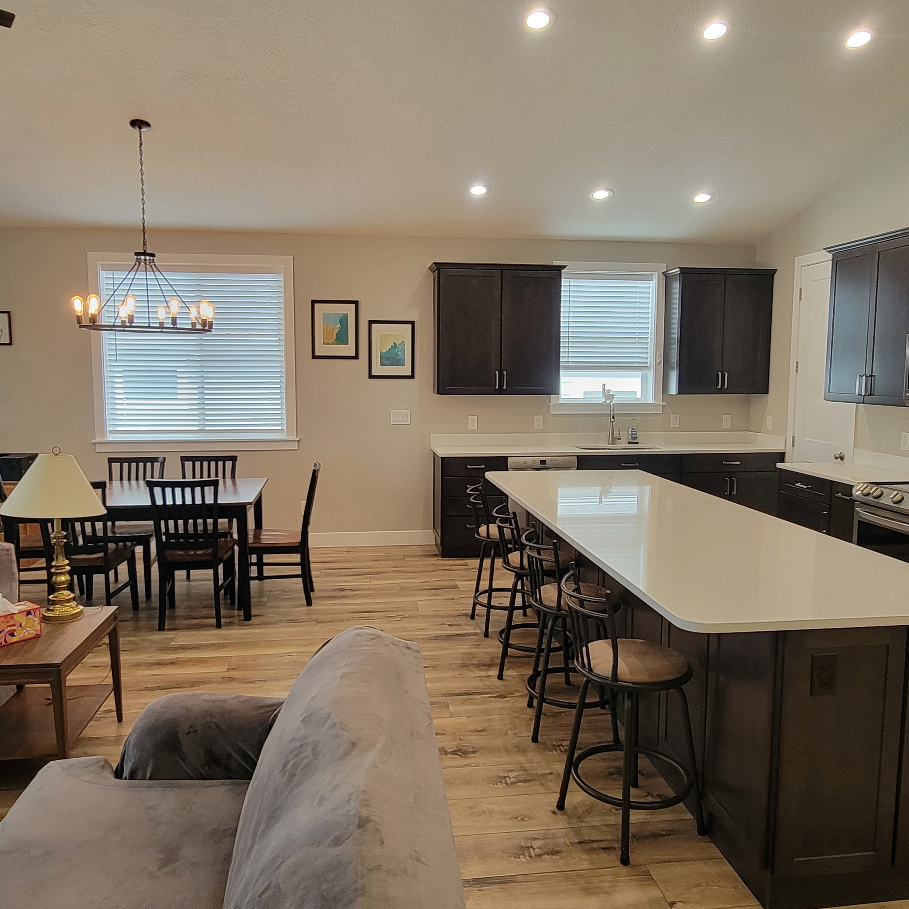 Open-concept living area featuring wood-finish flooring, recessed lighting, and a modern chandelier